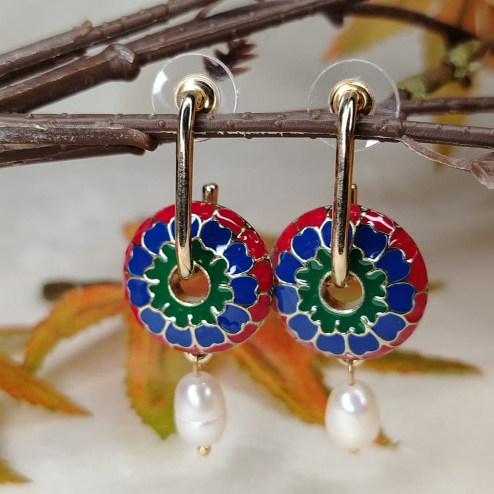 Colorful floral earrings with pearl drops on a branch and leaf background