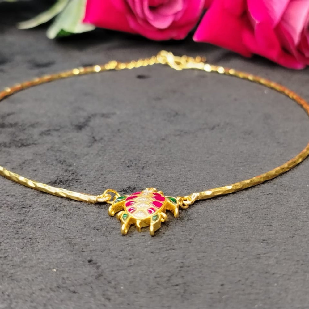 Gold necklace with a Turtle pendant on a dark surface with pink roses in the background