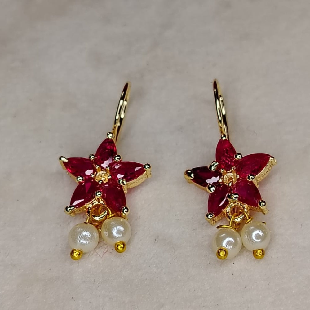 Pair of earrings with red crystal flower-like designs and pearl beads on a light background