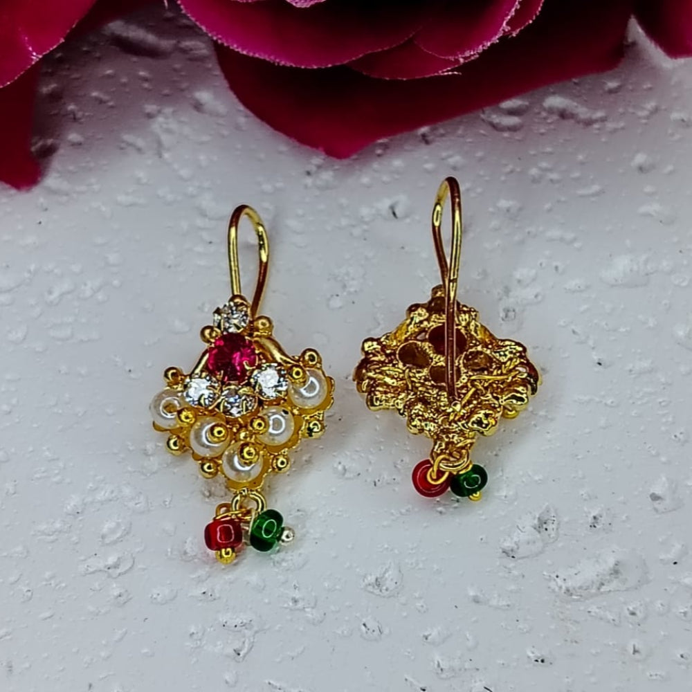 Gold earrings with red and green accents on a textured white surface.