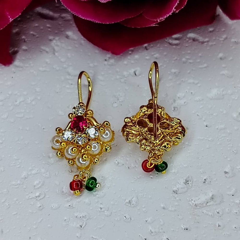 Gold earrings with red and green accents on a textured white surface.