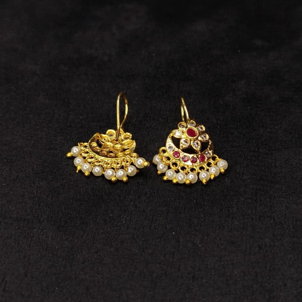 Pair of golden ear cuffs with gemstones on a black background