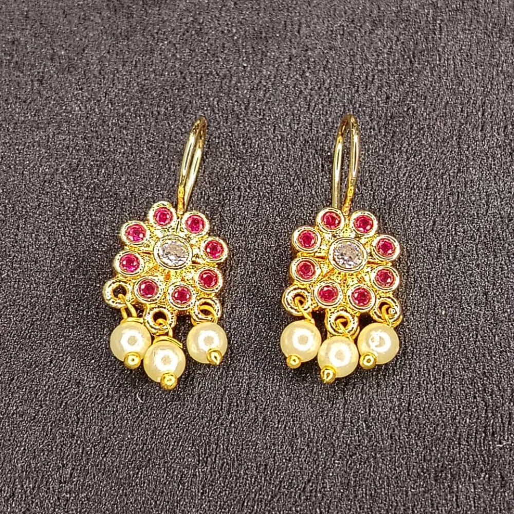 Pair of gold earrings with pearls and red stones on a gray background