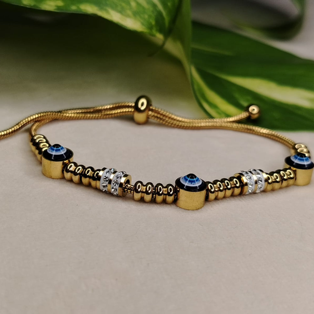 Gold bracelet with decorative beads on a neutral background