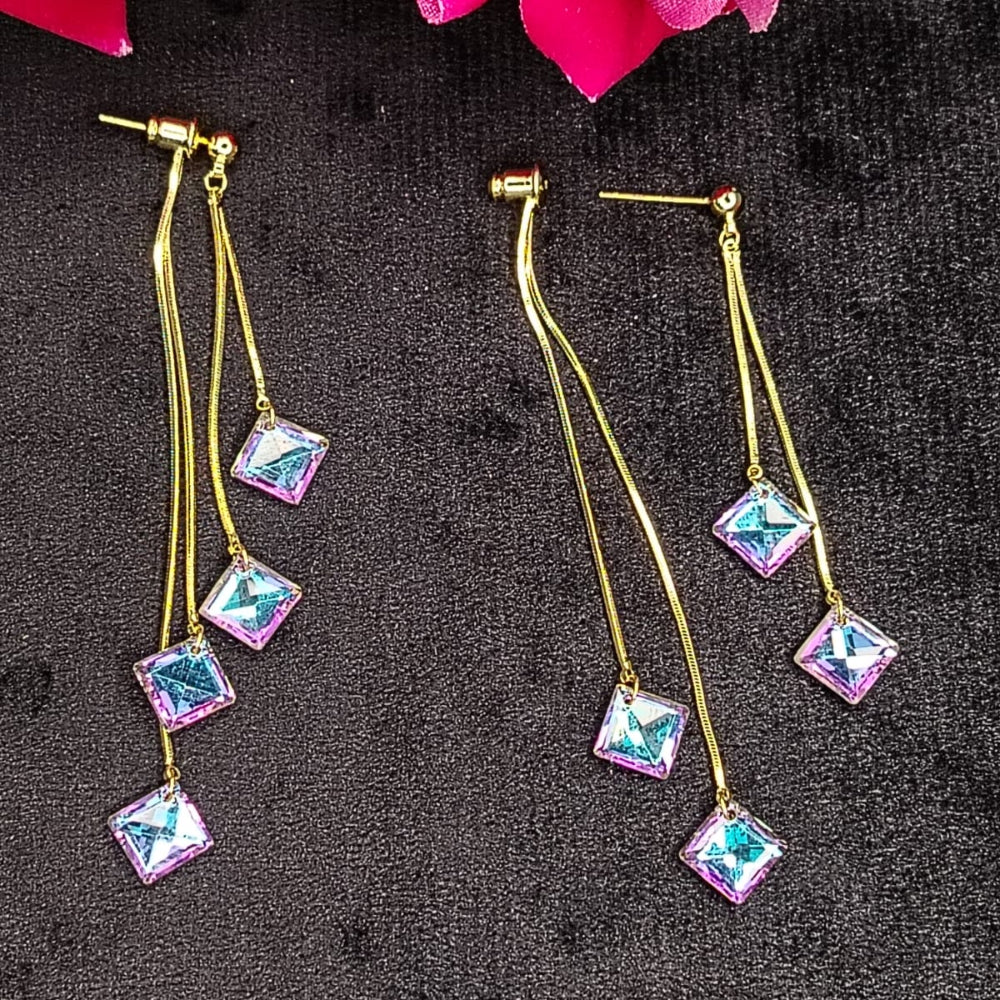 Pair of earrings with square rainbow crystals on a dark textured surface with pink flowers in the corner.