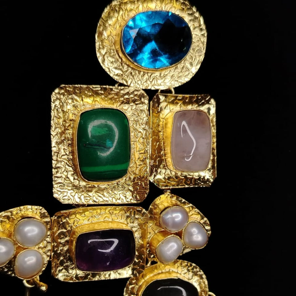 Gold pendant with gemstones and pearls on a black background