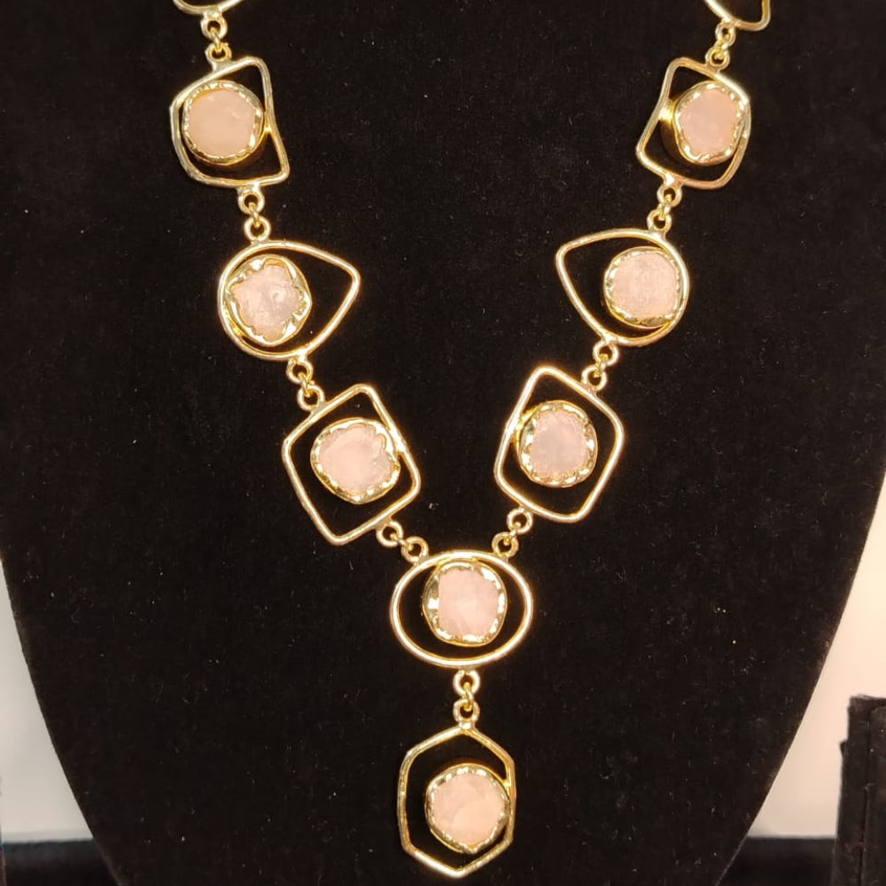 Necklace with gold chain and pink stones on a black stand