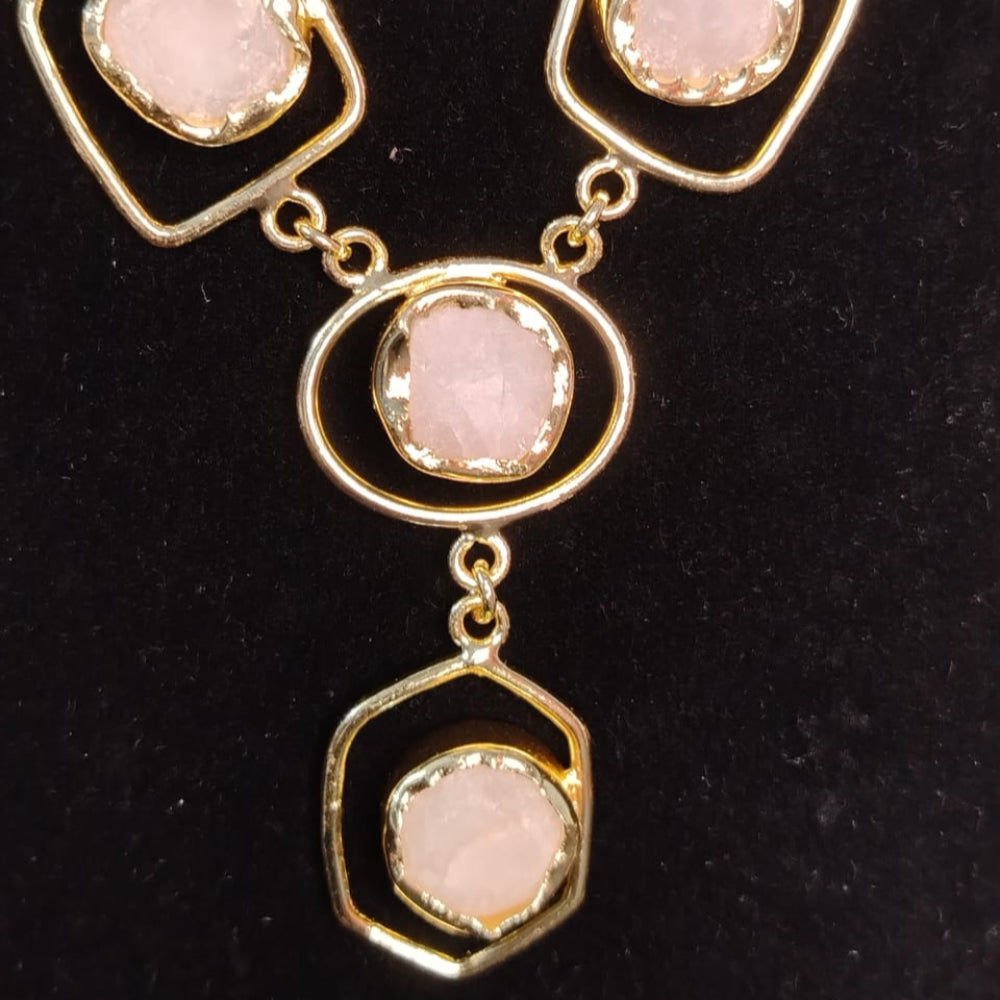 Necklace with pink stones and gold accents on a black background