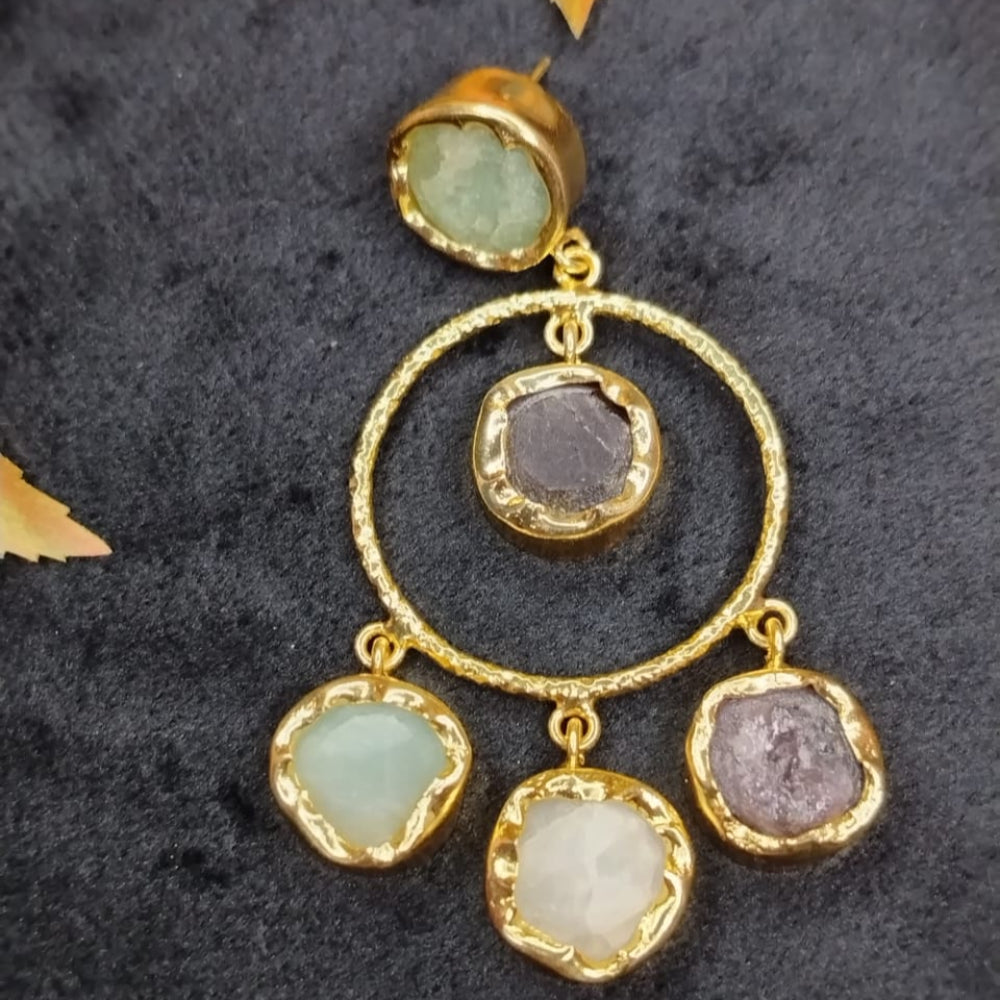 Golden earrings with Gemstones in hoop on a dark textured background