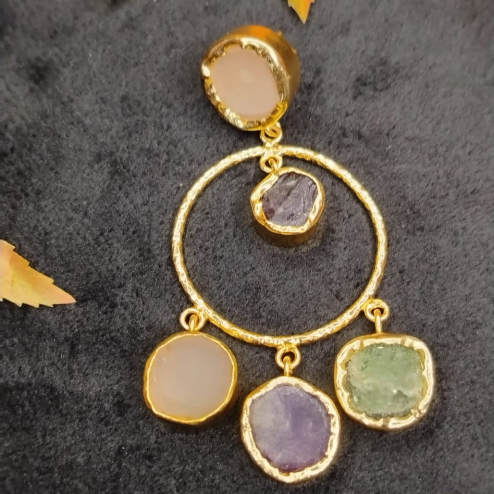 Golden hoop earring with colorful gemstones on a dark textured background