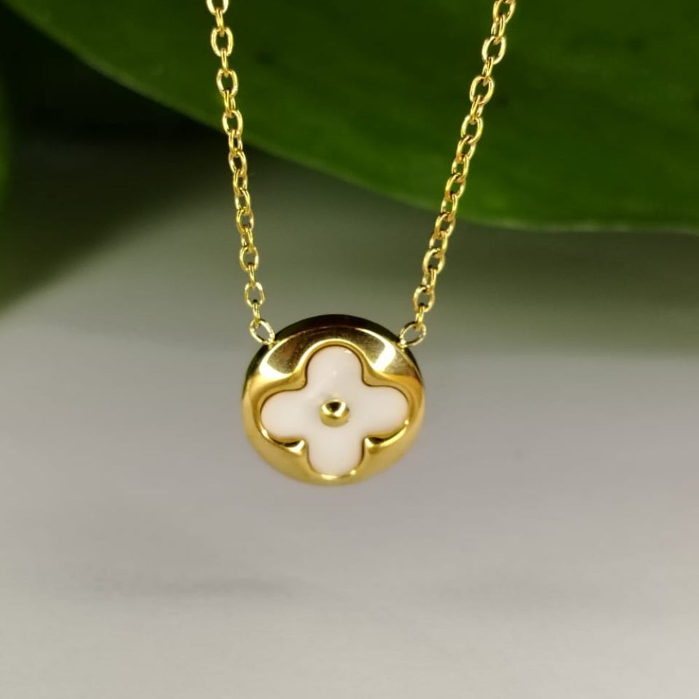 Gold necklace with a clover-shaped pendant on a light background