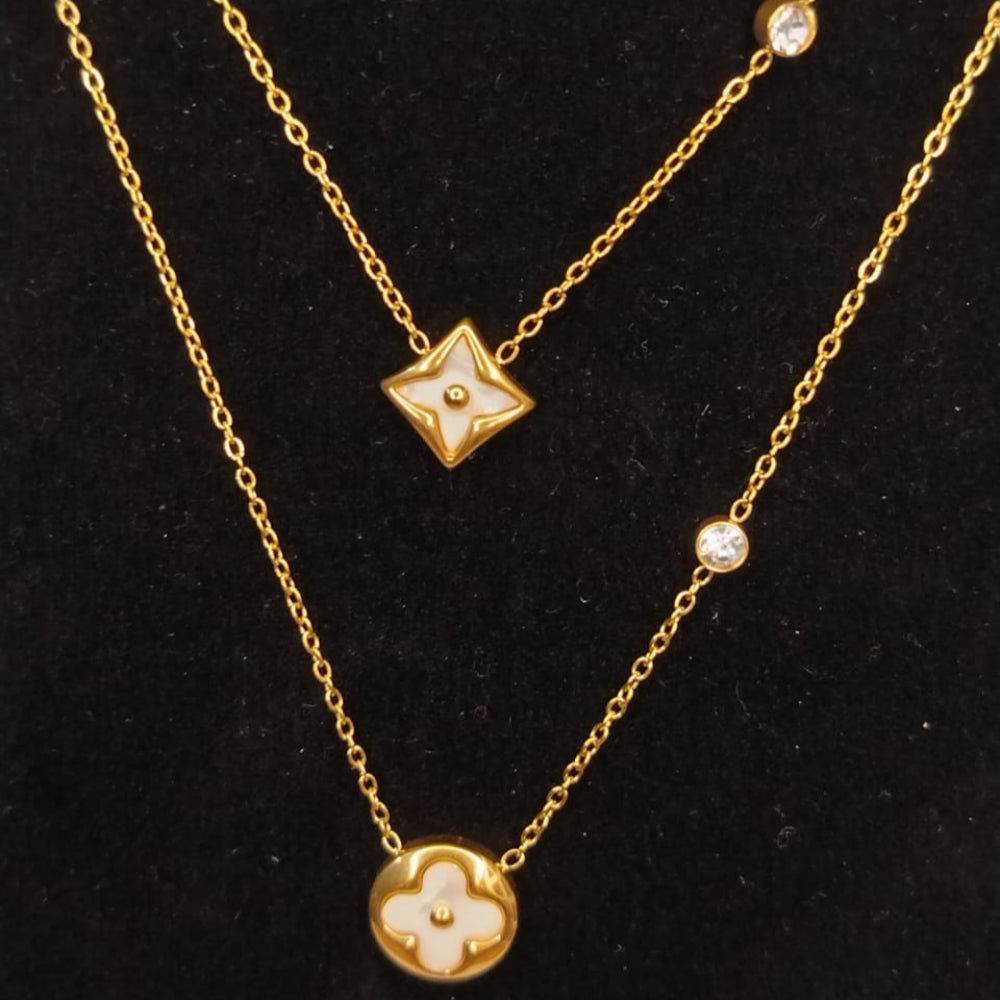 Two-layered gold necklaces with star and clover pendants on a black background