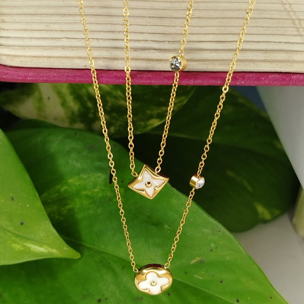 Gold necklaces with floral pendants on a green leaf