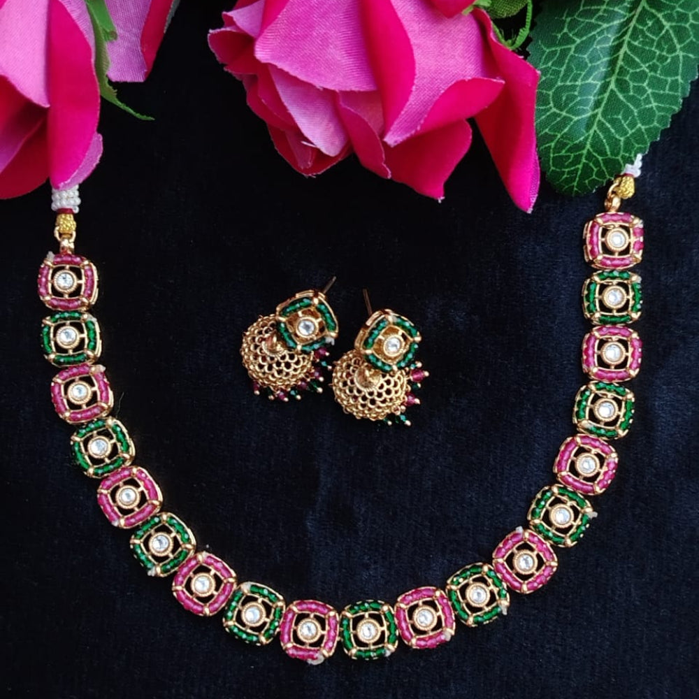 Necklace and earrings set with pink and green accents on a dark background with pink flowers.