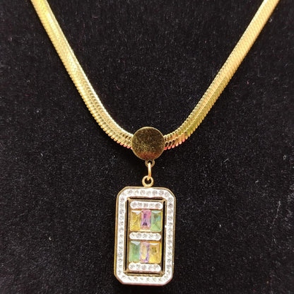 Gold necklace with a rectangular pendant on a black background
