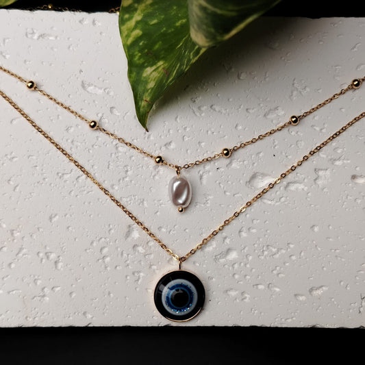 Double Layer Evil Eye Necklace with Pearl Drop on a textured White Background
