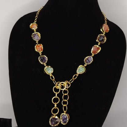 Necklace with multicolored gemstones on a black mannequin bust against a gray background