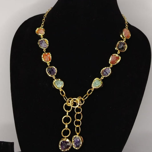 Necklace with multicolored gemstones on a black mannequin bust against a gray background