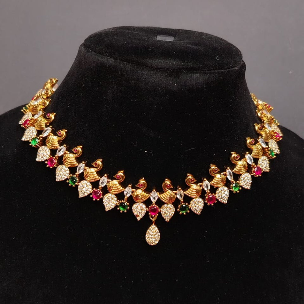 Gold necklace with gemstones on a black velvet stand against a gray background