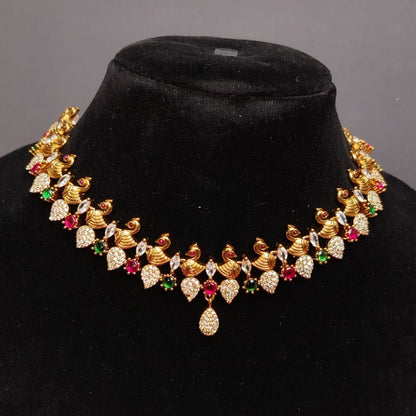 Gold necklace with gemstones on a black velvet stand against a gray background