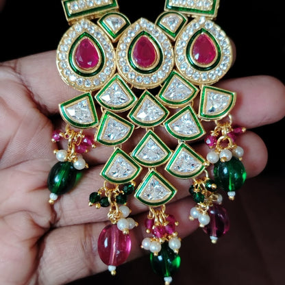 Ornate necklace with gemstones held in a hand against a dark background