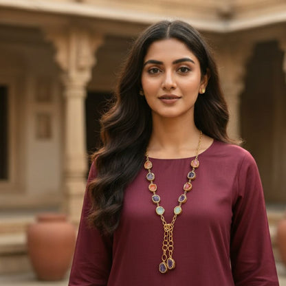 Woman wearing a maroon dress with a long necklace in an outdoor setting