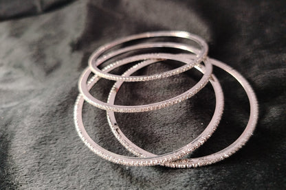 4 Sleek AD Bangles Lying Scattered on Black Fabric