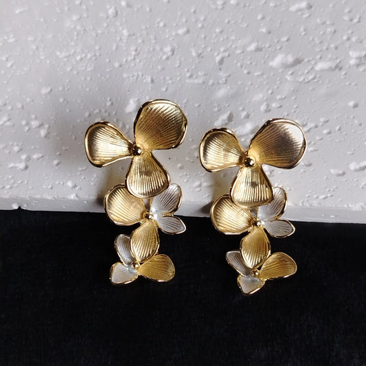 Pair of Gold and Silver Toned Three Layered Floral Earrings on Textured White Background