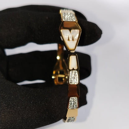 Golden Snakehood Bracelet Held by Black Gloved Hand against White Background