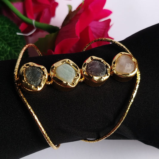 Golden Bracelet with 4 Multi-colored Natural Stones on a Black Glove with Flowers in the Background