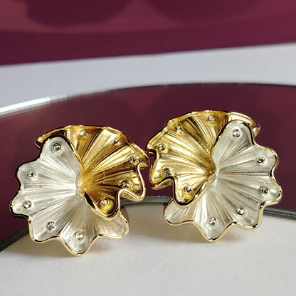 A pair of Gold and Silver Tone Floral Earrings with Diamond Accents on a White Surface with a Purple Background