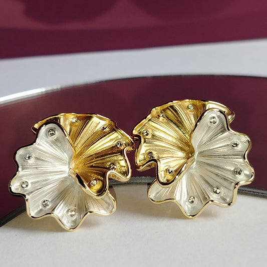 A pair of Gold and Silver Tone Floral Earrings with Diamond Accents on a White Surface with a Purple Background
