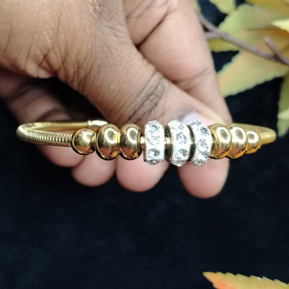 Golden Beads and Ad Loops Braclet Held by Hands on a Dark Background