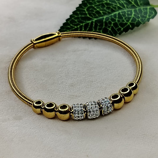 Bracelet with Golden Beads and American Diamond Loops on a Beige Background with Leaves