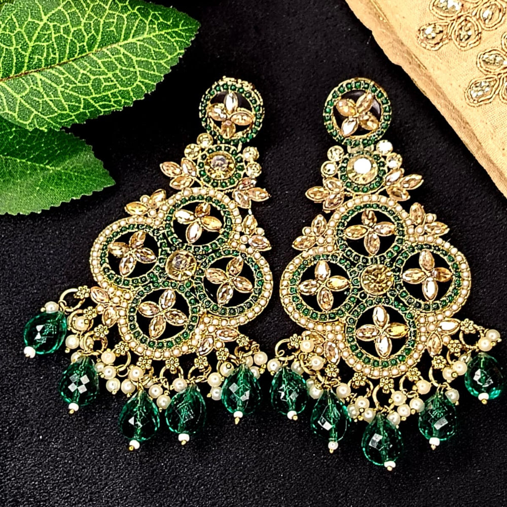 Ornate Gold and reen earrings on a Black Surface with Leaves and Fabric in the Background
