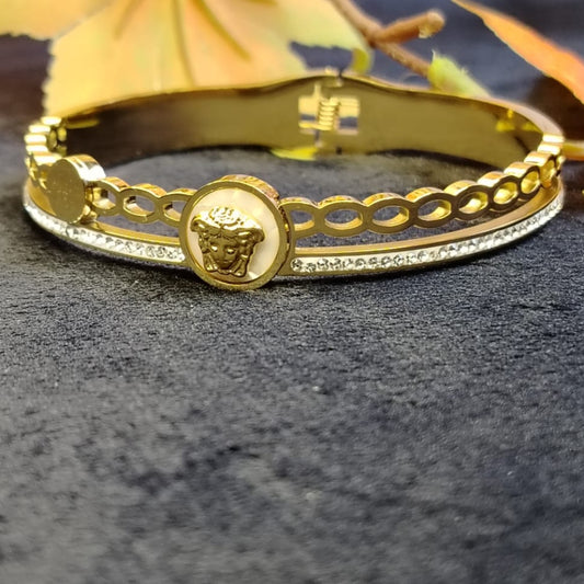 Gold bracelet with a brand logo on a dark textured surface