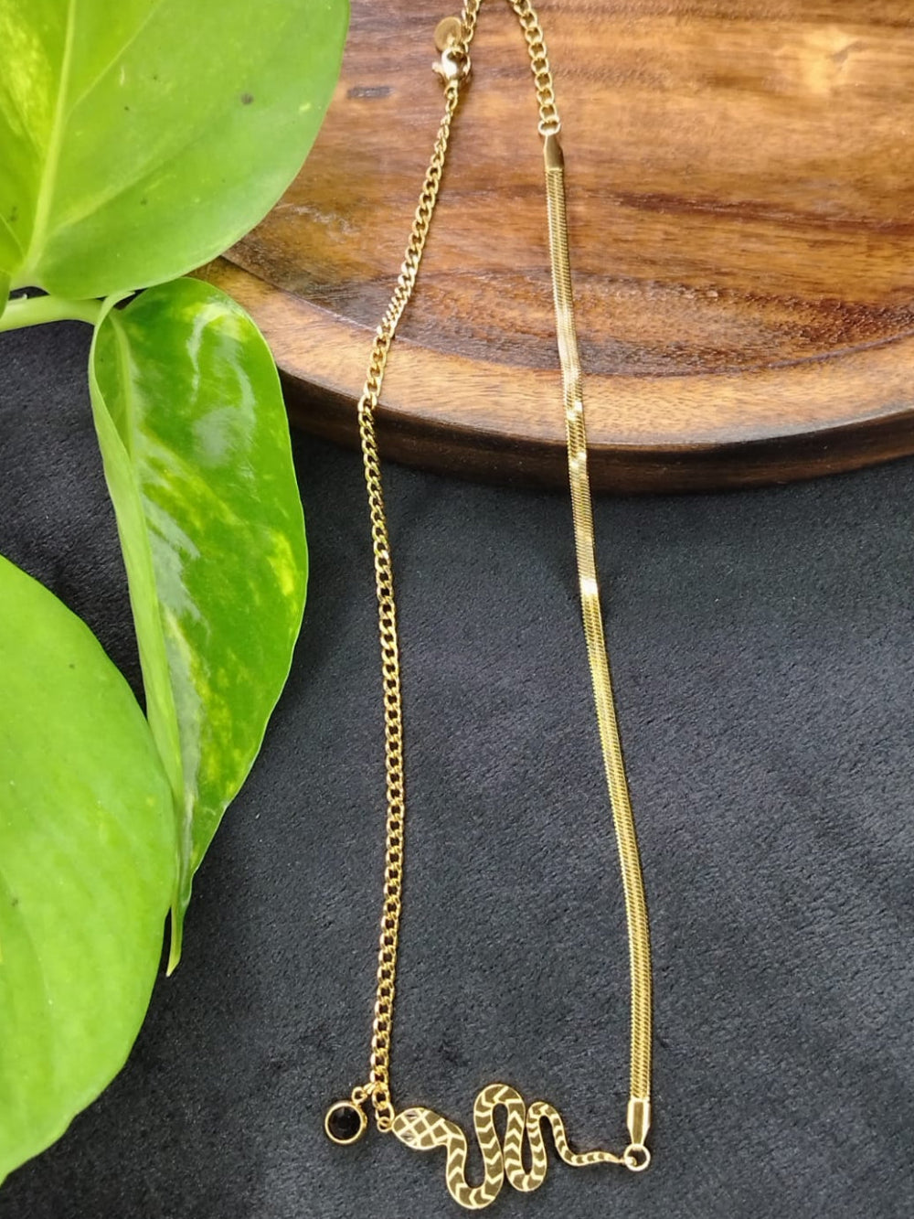 Anti-tarnish Golden Snake Pendant on a Wooden Tray with Green Leaves