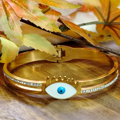 Golden Bracelet with Large Evil Eye with Diamond Accents on a Wooden Background