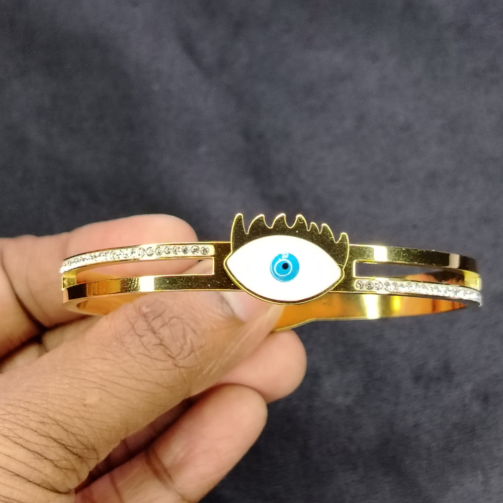 Hands Holding Golden Evil Eye Bracelet against a Dark Background