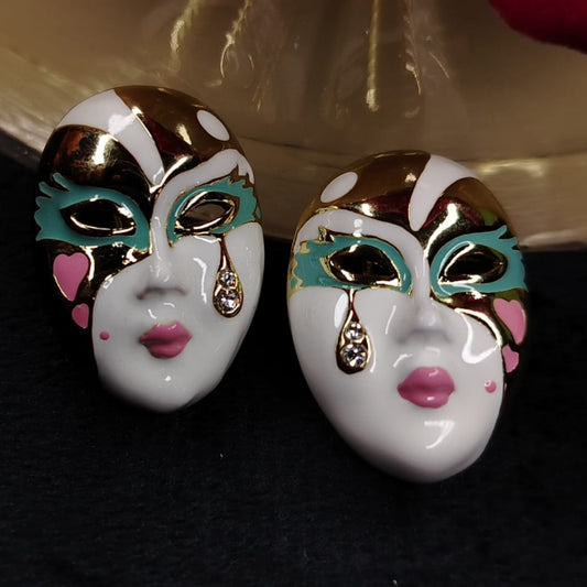 Pair of Mask-shaped Earrings with gold, Blue, and Pink Details with CZ on a dark Background.