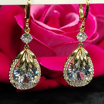 Golden American Diamond  Teardrop Earrings on Hoops against a Pink Rose Background