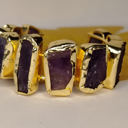 Gold-rimmed Amethyst Handcuff on A Beige Surface