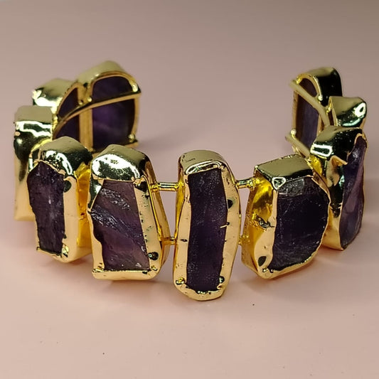 gold=rimmed Amethyst Handcuff on a Pink Surface
