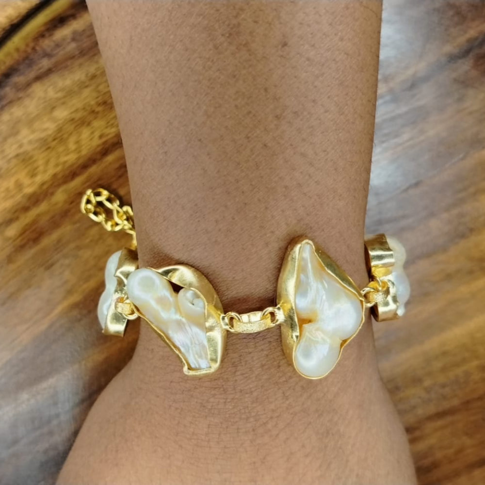 Golden Natural Pearl Bracelet on a Wrist aginst Wooden Background