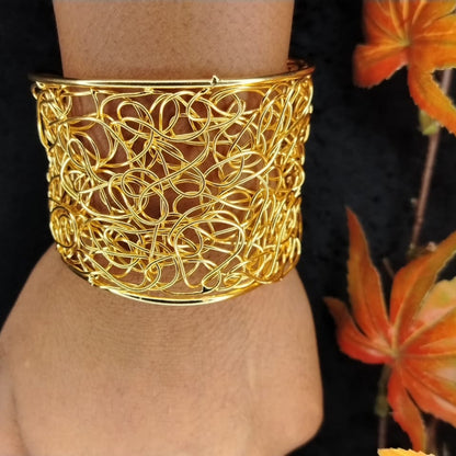 Broad Golden Filigree Handcuff on a Wrist with Back Background and Autumn Leaves