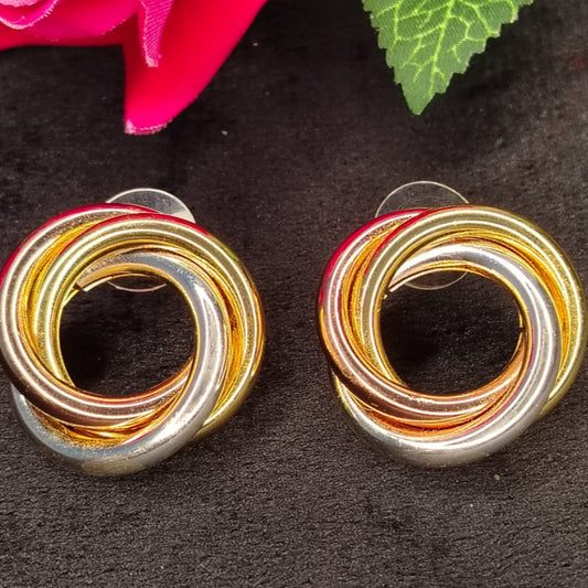 Pair of 3-tone Intertwined Earrings on a Dark Surface with a Pink Flower and Green Leaf.