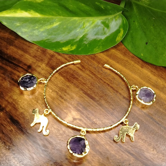 Golden Bracelets with Amethyst and Cheetah Charms on a Wooden Background
