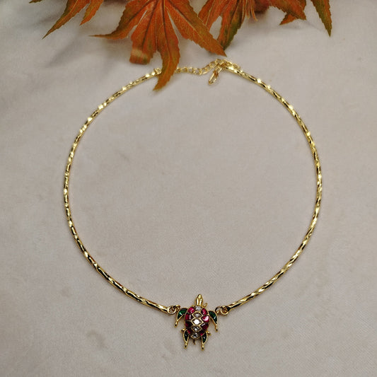 Golden necklace with a turtle pendant on a light background