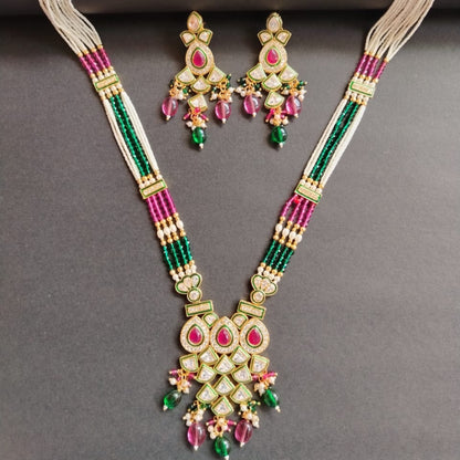 Ornate necklace and earrings set with pink and green beads on a gray background