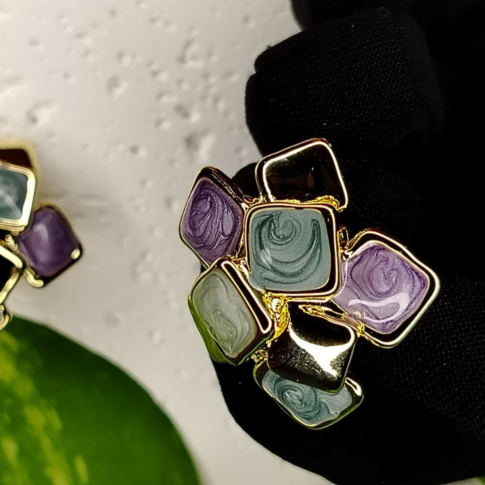 Multicored Eanamel Square Design Earrings with Gold Accents Held by a Gloved Hand